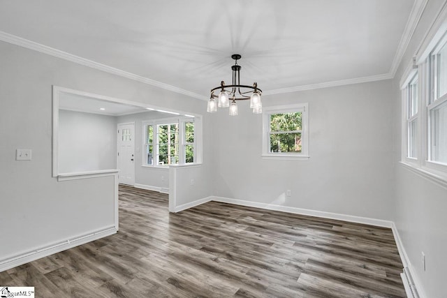 spare room with dark hardwood / wood-style floors, a wealth of natural light, ornamental molding, and a notable chandelier