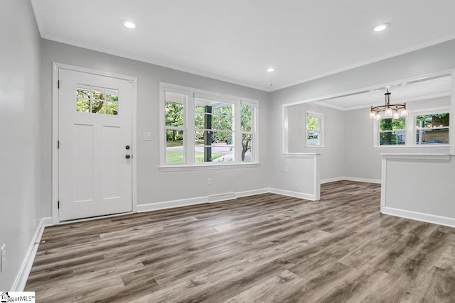 foyer entrance with hardwood / wood-style flooring, ornamental molding, and an inviting chandelier