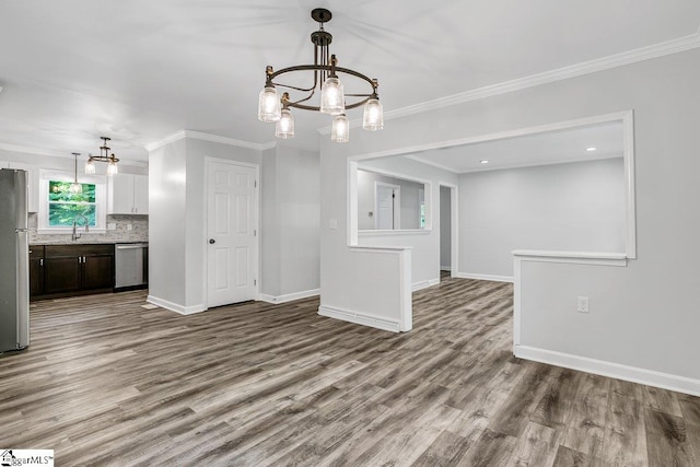 unfurnished dining area featuring light wood-type flooring, a notable chandelier, sink, and crown molding