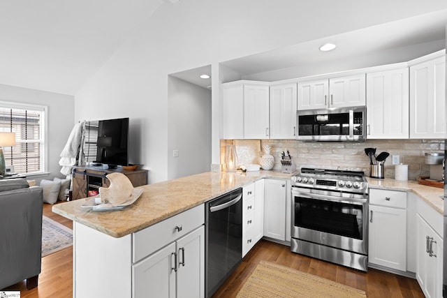 kitchen with kitchen peninsula, appliances with stainless steel finishes, lofted ceiling, and white cabinetry