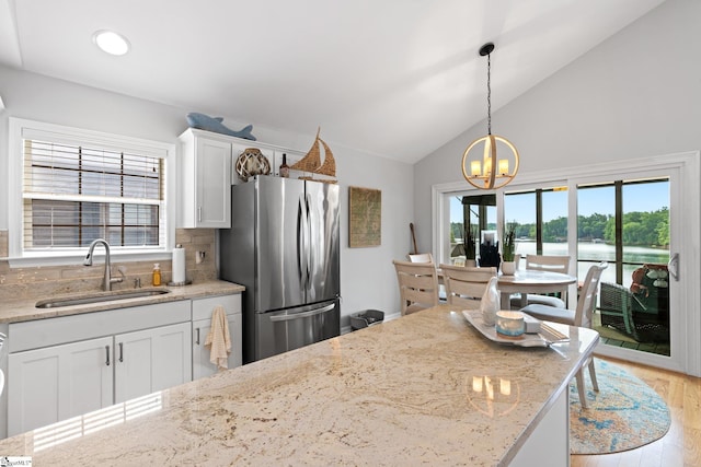 kitchen featuring white cabinets, sink, backsplash, and stainless steel refrigerator