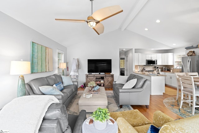 living room with ceiling fan, sink, light hardwood / wood-style flooring, and lofted ceiling with beams