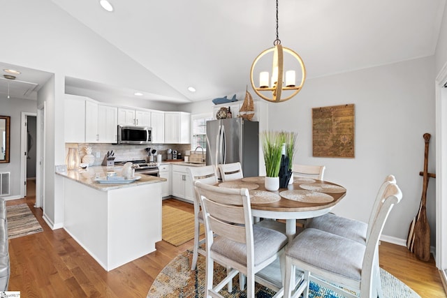 kitchen featuring kitchen peninsula, stainless steel appliances, backsplash, white cabinets, and sink