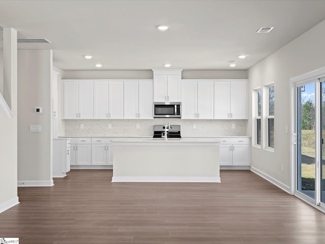 kitchen with an island with sink, sink, white cabinets, and light hardwood / wood-style floors