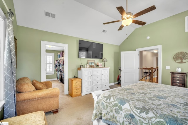 bedroom with a walk in closet, light colored carpet, vaulted ceiling, a closet, and ceiling fan