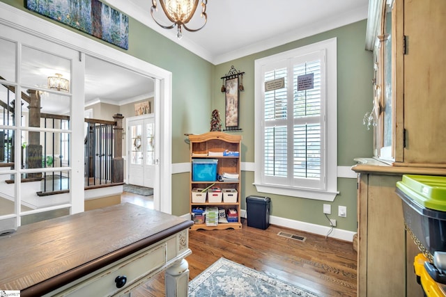 interior space featuring hardwood / wood-style flooring, ornamental molding, a wealth of natural light, and an inviting chandelier