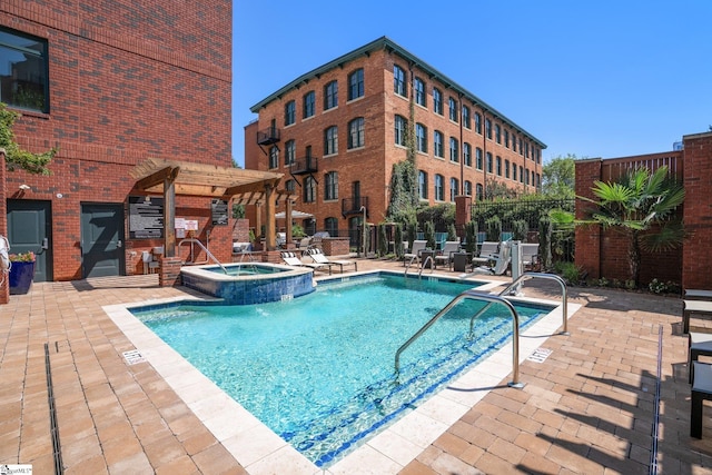 view of pool with a patio area, pool water feature, and a hot tub