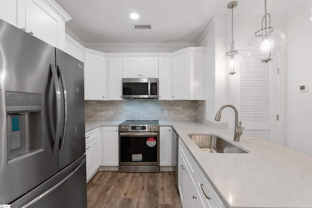 kitchen with decorative light fixtures, hardwood / wood-style floors, sink, appliances with stainless steel finishes, and backsplash