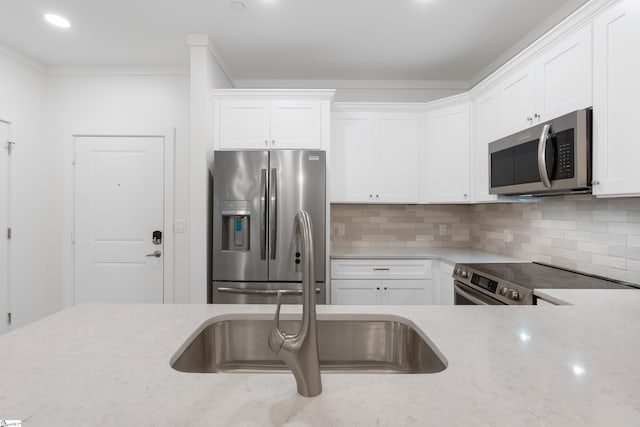 kitchen featuring white cabinetry, tasteful backsplash, crown molding, light stone countertops, and appliances with stainless steel finishes