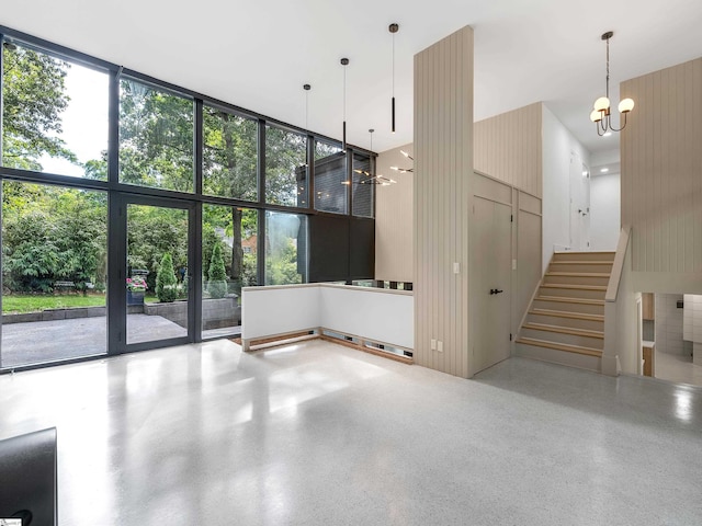 interior space with stairs, expansive windows, a notable chandelier, and speckled floor