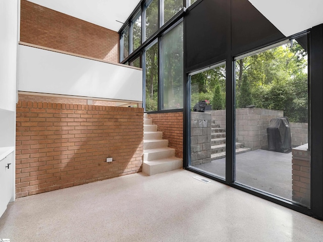 doorway to outside featuring brick wall and a towering ceiling