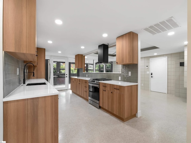 kitchen with island range hood, visible vents, brown cabinetry, appliances with stainless steel finishes, and a sink