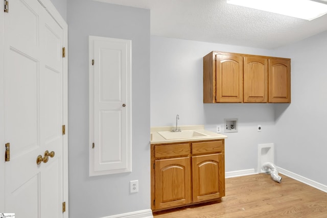 clothes washing area featuring hookup for a washing machine, light wood-style flooring, cabinet space, hookup for an electric dryer, and a sink