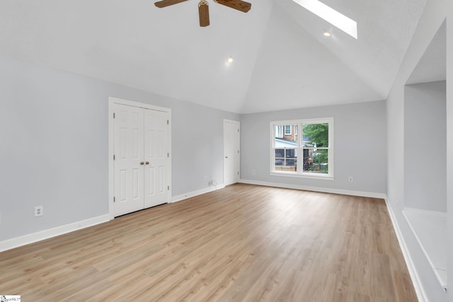 spare room with baseboards, a skylight, and light wood finished floors