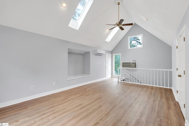 additional living space featuring baseboards, high vaulted ceiling, a skylight, an AC wall unit, and light wood-style floors