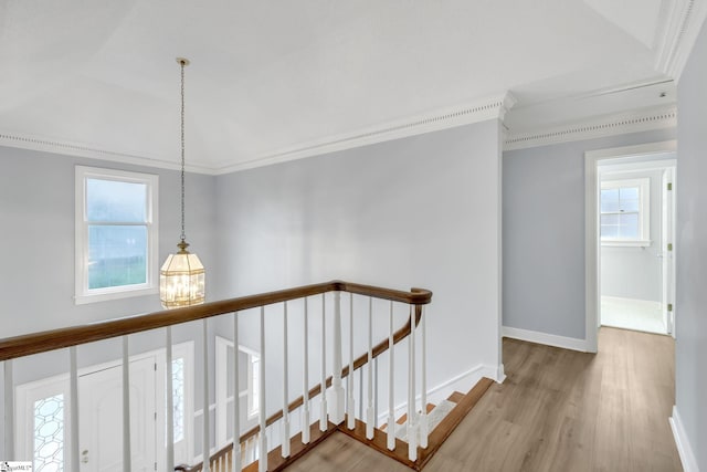 hallway featuring an upstairs landing, ornamental molding, and wood finished floors