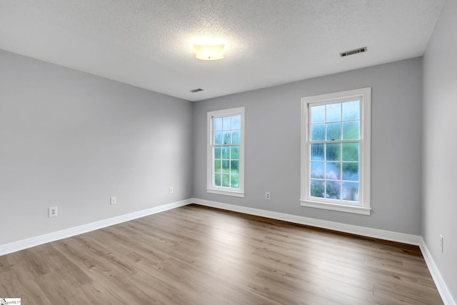 spare room featuring visible vents, baseboards, and wood finished floors