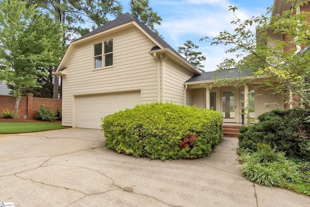 view of front of house with an attached garage, driveway, and roof with shingles