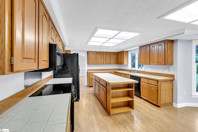 kitchen featuring tile countertops, light wood finished floors, a kitchen island, open shelves, and black appliances