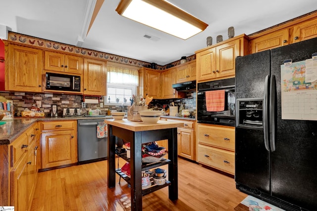 kitchen featuring decorative backsplash, light hardwood / wood-style floors, and black appliances