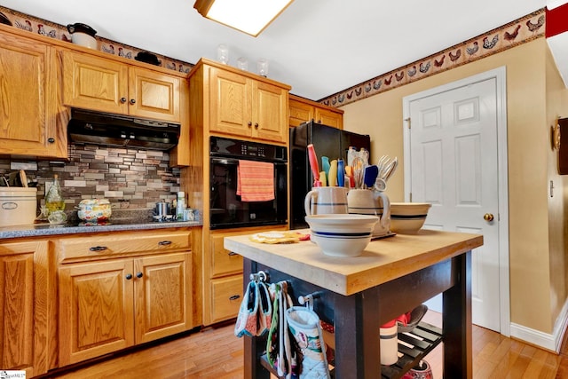 kitchen with light hardwood / wood-style flooring, black appliances, and backsplash