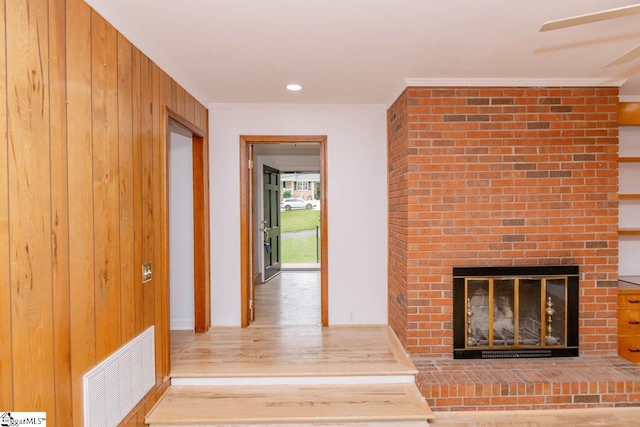 hallway with ornamental molding, wooden walls, and light hardwood / wood-style floors