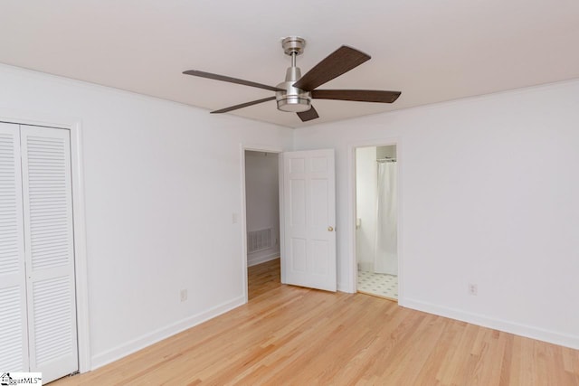 unfurnished bedroom with light wood-type flooring, ensuite bath, ceiling fan, and a closet