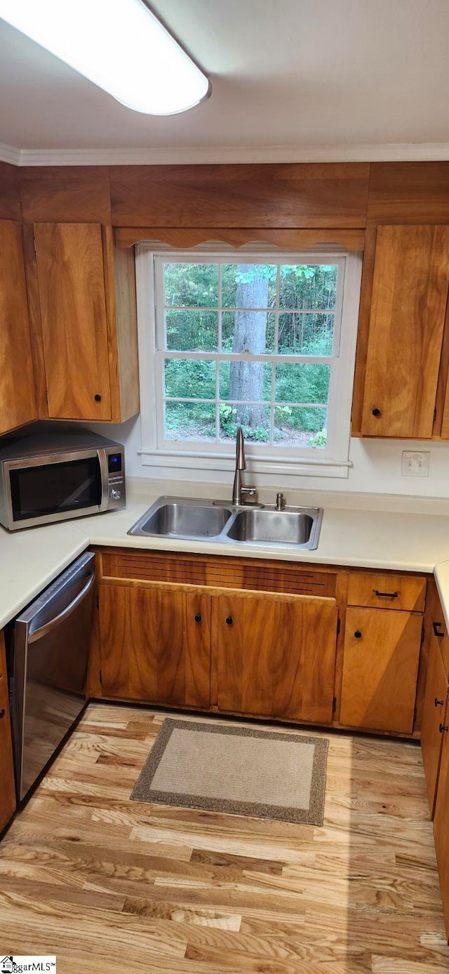 kitchen with stainless steel appliances, ornamental molding, and sink