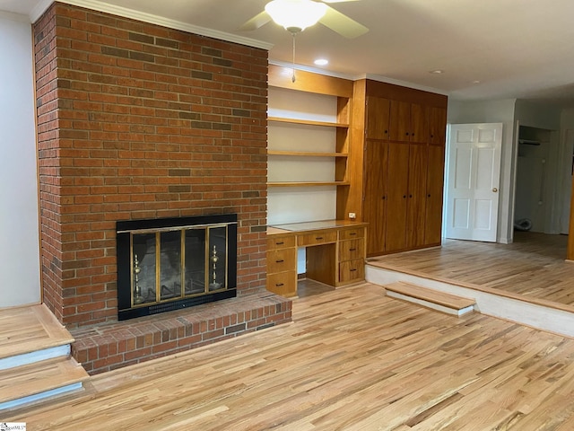 unfurnished living room with crown molding, a brick fireplace, and light hardwood / wood-style floors