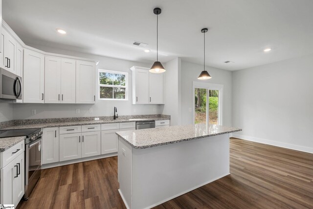 kitchen featuring appliances with stainless steel finishes, pendant lighting, dark hardwood / wood-style floors, light stone countertops, and white cabinetry