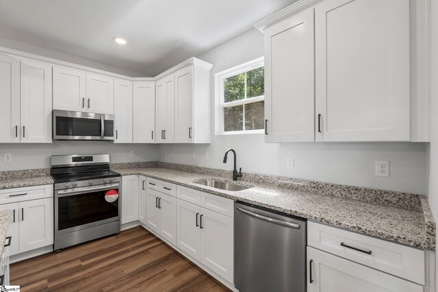 kitchen with sink, appliances with stainless steel finishes, white cabinetry, and dark hardwood / wood-style floors