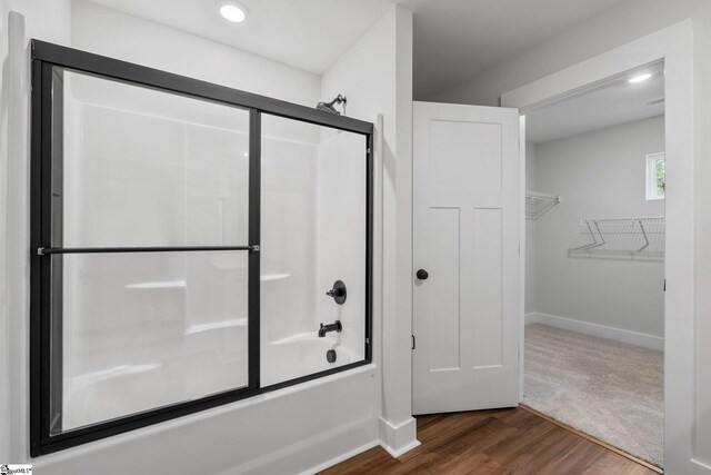 bathroom featuring hardwood / wood-style flooring and shower / bath combination with glass door