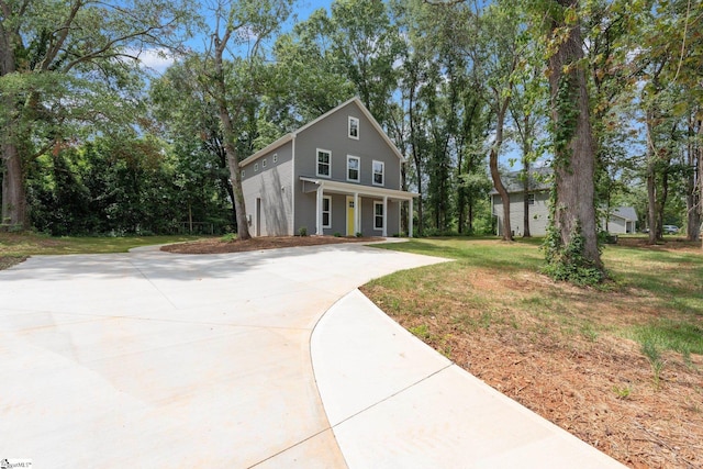 view of front of house featuring covered porch, a garage, and a front lawn