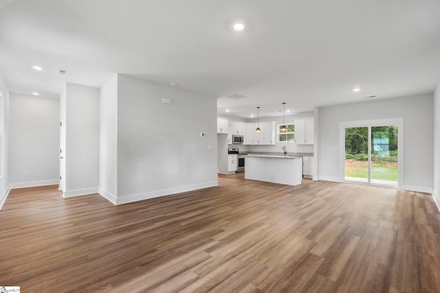 unfurnished living room featuring hardwood / wood-style floors and sink