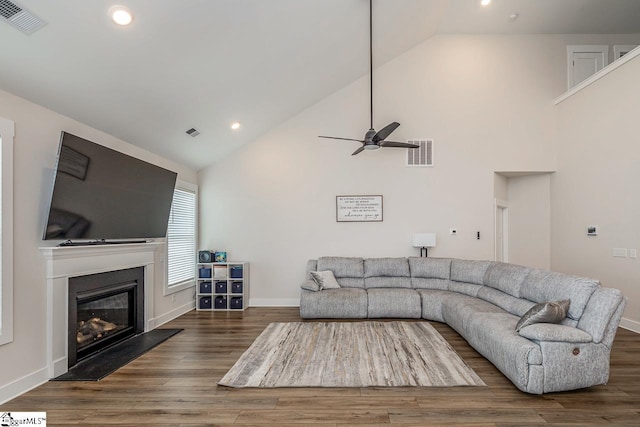 living room featuring dark wood-type flooring, a glass covered fireplace, and visible vents