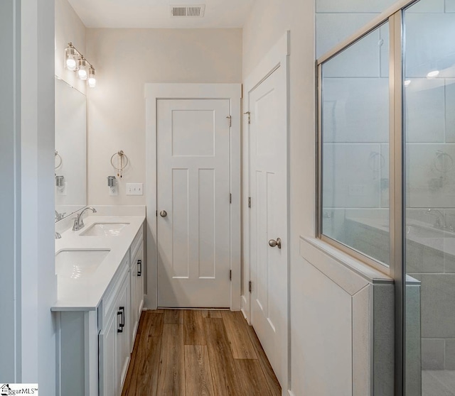 bathroom featuring double vanity, visible vents, a sink, and wood finished floors