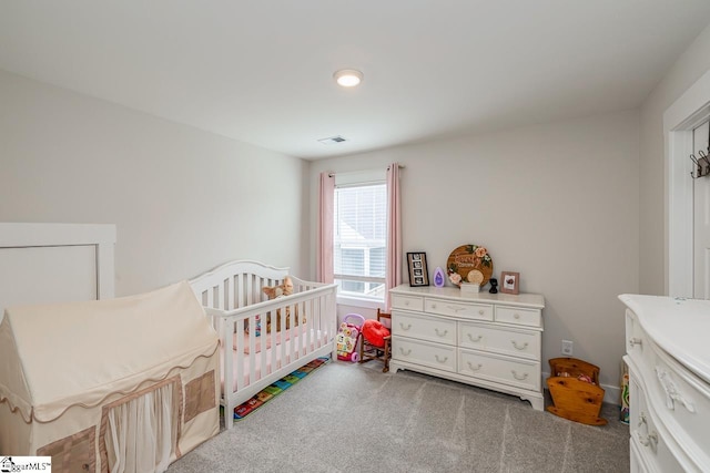 bedroom featuring carpet floors, a crib, and visible vents