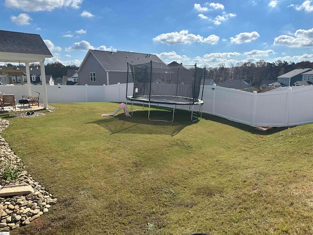 view of yard with a trampoline, a residential view, and a fenced backyard