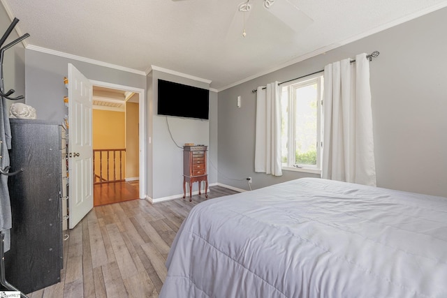 bedroom featuring baseboards, ornamental molding, a textured ceiling, and light wood-style floors