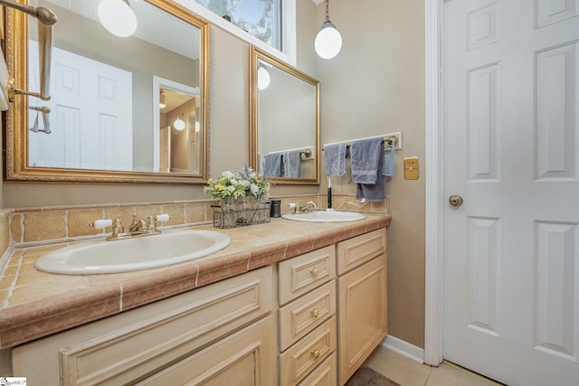 bathroom featuring double vanity, baseboards, a sink, and tile patterned floors