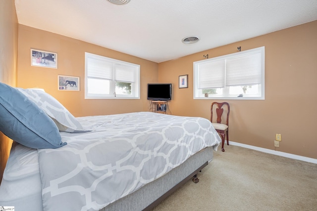 bedroom featuring light colored carpet, visible vents, baseboards, and multiple windows