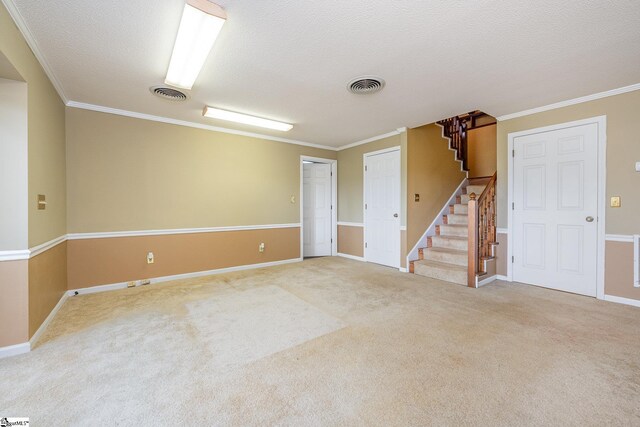 carpeted spare room featuring visible vents, crown molding, and stairs