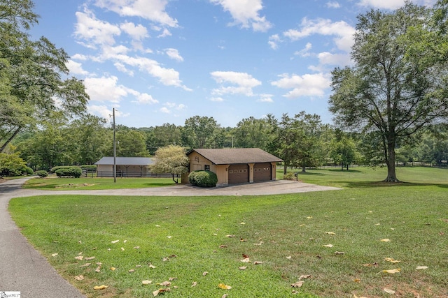 view of community featuring a detached garage, fence, and a yard