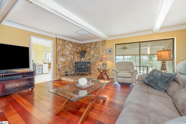 living room featuring beam ceiling, wood finished floors, and a wood stove