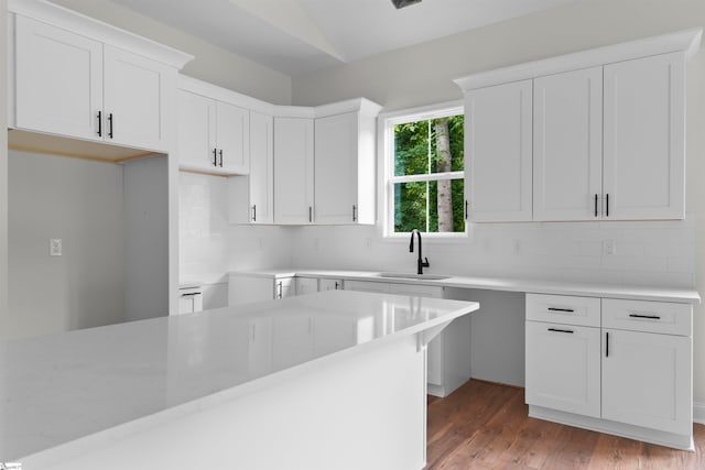 kitchen featuring sink, light hardwood / wood-style flooring, white cabinetry, and decorative backsplash