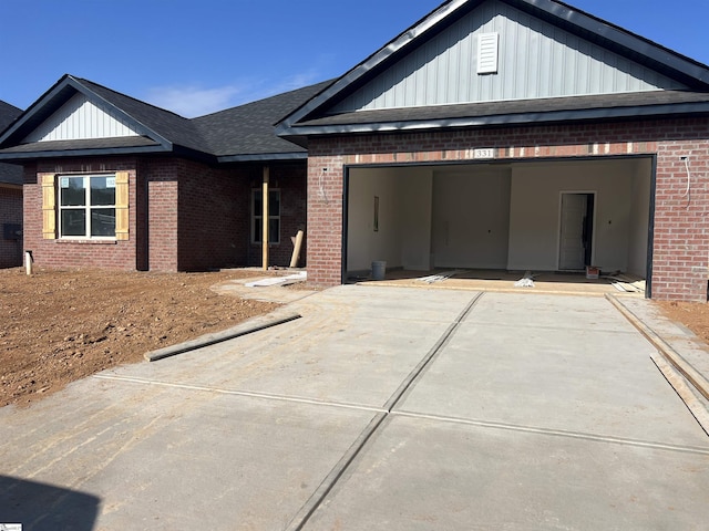 view of front facade featuring an attached garage, roof with shingles, concrete driveway, and brick siding