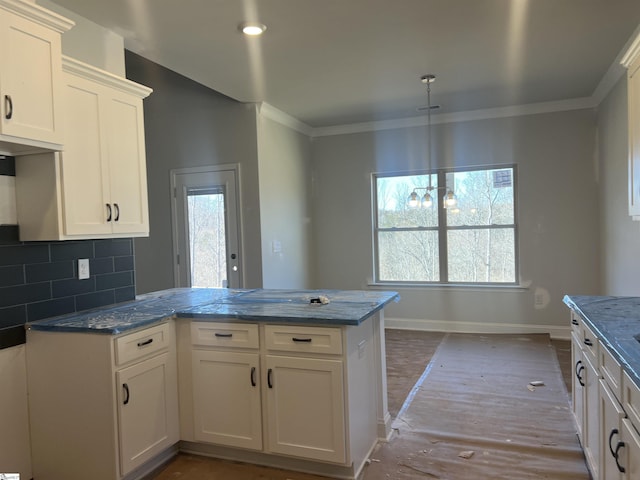 kitchen featuring tasteful backsplash, visible vents, dark stone counters, baseboards, and ornamental molding