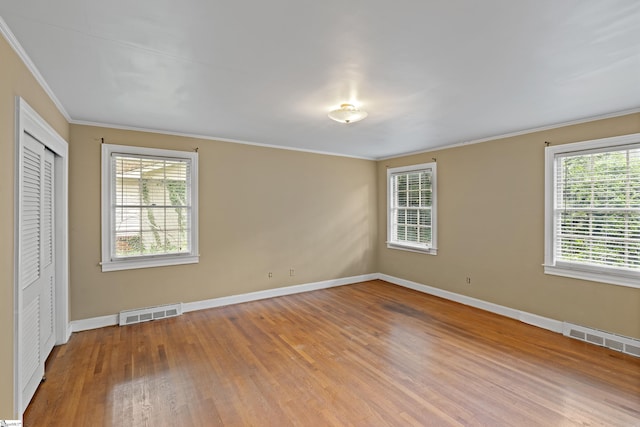 empty room featuring visible vents, baseboards, and wood finished floors