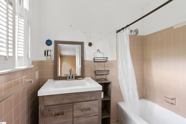 bathroom featuring shower / bath combination with curtain, a wainscoted wall, tile walls, and vanity