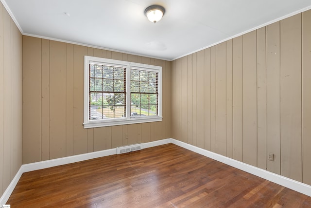 unfurnished room with ornamental molding, wood finished floors, visible vents, and baseboards